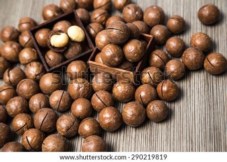 Macadamia nut shell snack in wood box and on wooden brown background