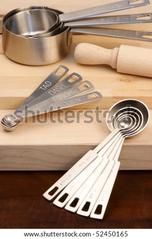 set of measuring spoons and other kitchen utensils on wood cutting board