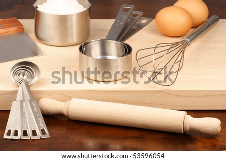 set of measuring spoons and other kitchen utensils on wood cutting board