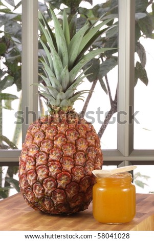 Small jar with organic homemade pineapple jam on wood counter with pineapple