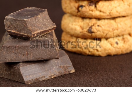 Fresh baked Stack of chocolate chip cookies accompanied with  large pieces of dark chocolate to make it sweeter