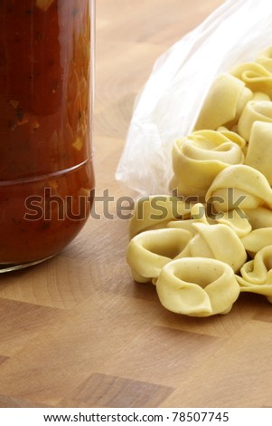 fresh and raw wholegrain tortellini  pasta with tomato sauce jar , the perfect ingredients to make an easy and fast delicious meal.