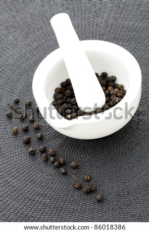 ceramic  mortar and pestle full with aromatic black peppercorns