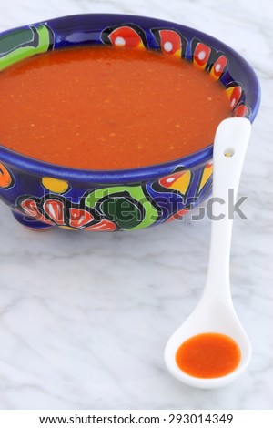 Artisan hot taco sauce in vintage talavera bowl, with a delicious fresh hot flavor,  on vintage carrara marble table.