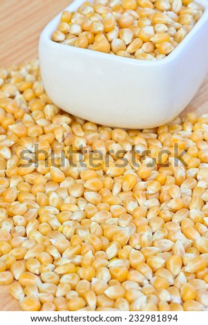 closeup of raw corn seeds in white bowl on wood table for food concept or background ; selective focus