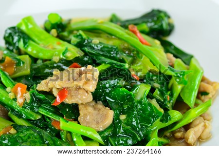 closeup of  kale vegetable fried with oil and pork ; selective focus