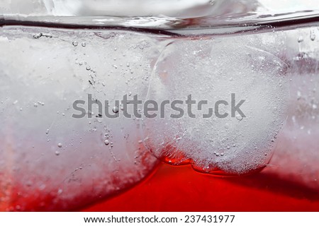 macro of red beverage with ice in circle drinking glass for  abstract background ; selective focus