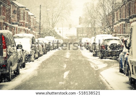 Manchester, England. Cars cover, houses of snow on street. The winter storm, causing flight delays and traffic problems.
