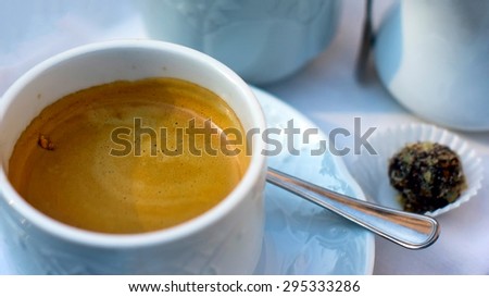Espresso coffee in a white cup and candy in a white wrapper