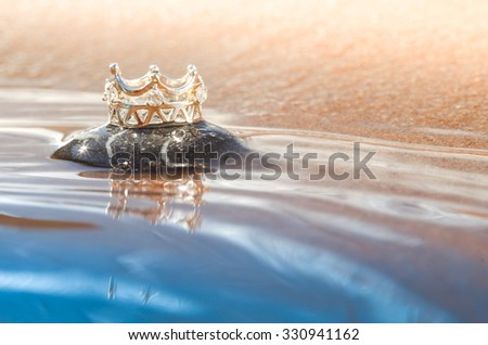 A beautiful and shiny silver crown on a stone at the beach/Beautiful silver crown/Crown on a beach