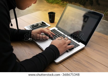 Cropped shot Silhouette of a man\'s hands using a laptop at home, rear view of business man hands busy using laptop at office desk,  typing on computer sitting wooden table, phone on table, filter sun