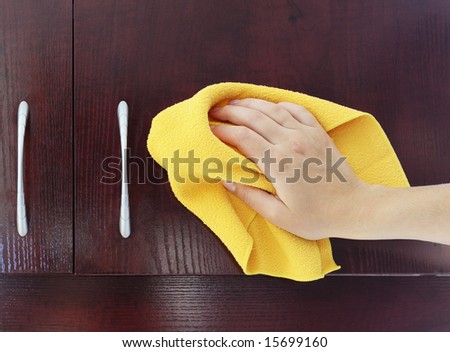 woman\'s hand polishing the door of mahogany kitchen closet