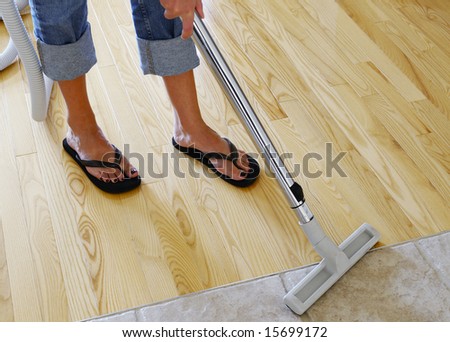 woman cleaning hardwood and tile floor with central vacuum cleaner