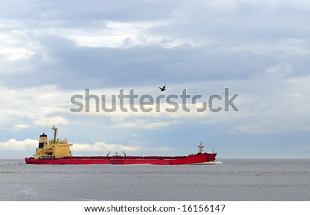 Cargo ship in open sea under cloudy blue sky