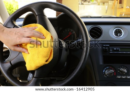 Woman's hand with microfiber cloth polishing steering wheel of an SUV car