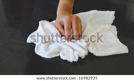 Woman\'s hand with cotton terry towel wiping stone counter