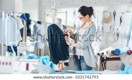 Beautiful Woman fashion, designer,  Working with Tailoring Mannequin, Adjusting Blouse. Her Studio is Bright and Sunny, Mannequins Standing around, Clothes Hanging, Colorful Fabrics Lying on the Table