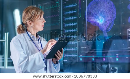 Female Scientist Uses Tablet Computer In the Modern Brain Study Laboratory and Monitors EEG Reading and Brain Model Functioning.