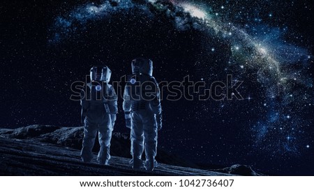 Crew of Two Astronauts in Space Suits Standing on the Moon Looking at the The Milky Way Galaxy. High Tech Concept of Moon Colonization and Space Travel.