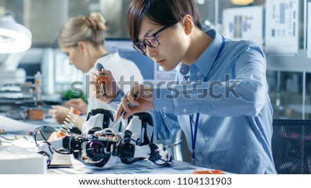 Electronics Engineer Works with Robot, Soldering Wires and Circuits. Computer Science Research Laboratory with Specialists Working.