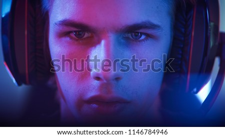 Portrait of the Young Handsome Pro Gamer Playing in Online Video Game. Neon Colored Room. e-Sport Cyber Games Internet Championship.