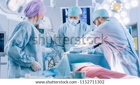 Diverse Team of Professional Surgeons Performing Invasive Surgery on a Patient in the Hospital Operating Room. Surgeonst Use  and other Instruments, Anesthesiologist Monitors Vitals.