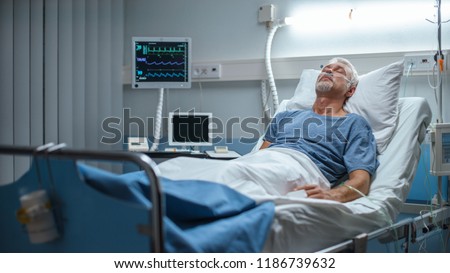 In the Hospital Senior Patient Rests, Lying on the Bed. Recovering Man Sleeping in the Modern Hospital Ward.