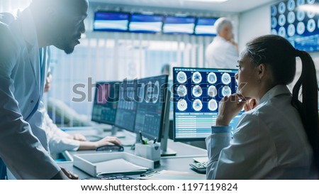 Two Medical Scientists in the Brain Research Laboratory work. Neuroscientists Use Personal Computer with MRI, CT Scans Show Brain Images.