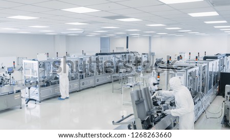 Sterile High Precision Manufacturing Laboratory where Scientists in Protective Coverall\'s Turn on Machninery, Use Computers and Microscopes, doing Pharmaceutics, Biotechnology Semiconductor Research.