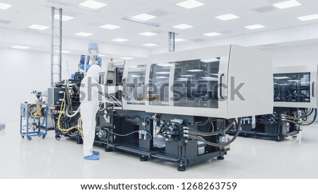 On a Factory Scientist in Sterile Protective Clothing Work on a Modern Industrial 3D Printing Machinery. Pharmaceutical, Biotechnological and Semiconductor Creating / Manufacturing Process.
