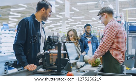 At the Supermarket: Checkout Counter Professional Cashier Scans Groceries and Food Items. Clean Modern Shopping Mall.