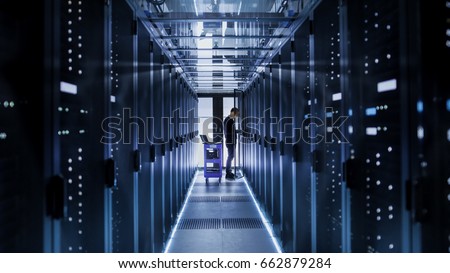 IT Engineer With Crash Cart Puts Hard Drives into Open Rack Server Cabinet. He\'s Working in Big Data Center.