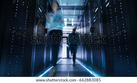 Shot of Corridor in Large Data Center Full of Walking and Working People. Pronounced Motion Blur.