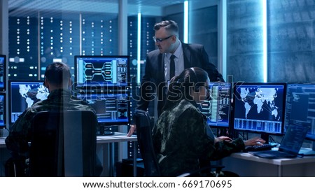 Team of Government Agents Tracking Fugitive with Boss\'s Survillance in Big Monitoring Room Full of Computers with Animated Screens.