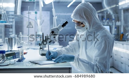In a Secure High Level Research Laboratory Scientist Writing Down Experiment Results.