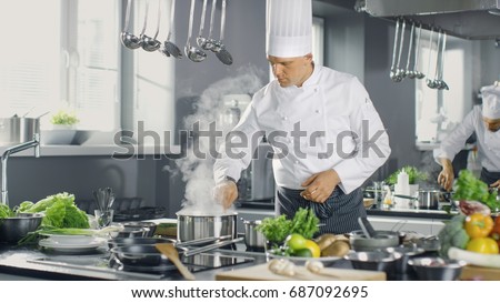 Famous Chef of a Big Restaurant Prepares Dishes with His Help of Cooks. Modern Kitchen is Made of Stainless Steel and Full of Cooking Ingredients.
