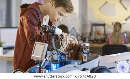 Boy Works on a Fully Functional Programable Robot with Bright LED Lights for His School Robotics Club Project.