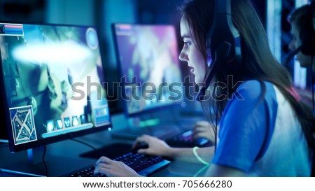 Professional Girl Gamer Plays in MMORPG/ Strategy Video Game on Her Computer. She\'s Participating in Online Cyber Games Tournament, Plays at Home, or in Internet Cafe. She Wears Gaming Headset.