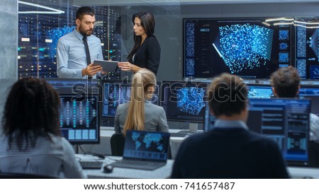 Head of the Department and Project Manager Discuss Work Process Using Data on Tablet Computer. Multi-Ethnic Team Builds Neural Network with Integrated Machine Learning.
