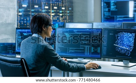 In the System Control Room Technical Operator Works at His Workstation with Multiple Displays Showing Graphics. IT Technician Works on Artificial Intelligence, Big Data Mining, Neural Network Project.