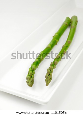 A couple of asparagus stalks laying on a serving dish.
