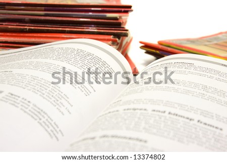 Open book with stack of magazines in background.