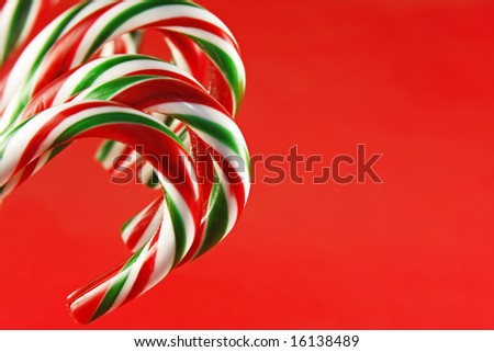 Red and green striped peppermint candy canes against a red background.