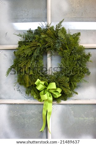 Christmas wreath hanging from a frosted glass pane door.