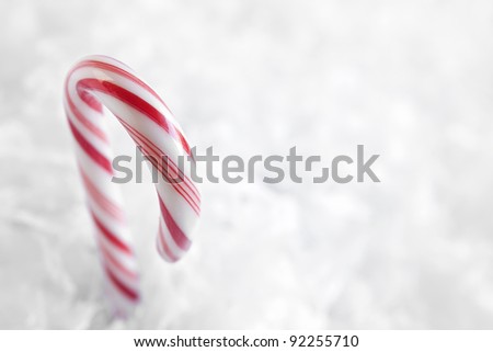 Red and white candy canes surrounded by faux snowflakes against a white background.