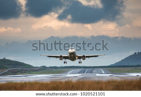 Airplane taking off in summer day front view, horizontal, rain clouds on background/ Plane fly up/ Take off aircraft from the airport, low over the runway Vacation, aviation, travel, trip - concept