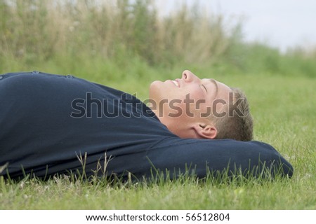 Young man lying in the green grass taking a nap