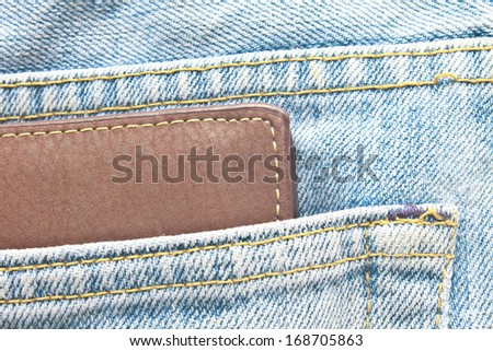 Brown wallet in jeans trousers back pocket, close up texture
