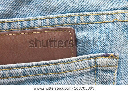 Brown wallet in jeans trousers back pocket, close up texture