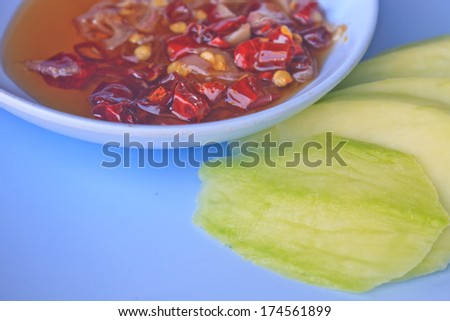 mangoes with sauce, mangoes dipped into a sweet fishy paste with dried shrimp and red onions in plate